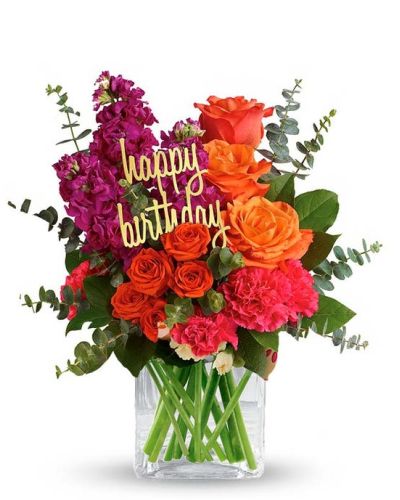 <p>Bring the celebration straight to their door with a birthday bouquet that’s bursting with color, cheer, and festive flair. This vibrant arrangement is designed to light up the room and their day, making it the perfect surprise for marking another year with joy. With its bold palette and upbeat personality, it’s a gift that speaks volumes in every petal.</p>
<p>The bouquet features a spirited mix of orange roses, orange spray roses, and pink carnations, arranged with care in a sleek glass cube vase. Each bloom is chosen for its freshness and vibrancy, creating a composition that feels lively and full of personality. A cheerful “Happy Birthday” pick may be included, depending on availability, adding a playful finishing touch to the arrangement.</p>
<p>This design is ideal for friends, coworkers, or loved ones who appreciate vivid colors and energetic style. Its modern look and fresh hues make it a standout for any birthday celebration, from casual lunches to surprise deliveries. The arrangement brings a touch of excitement to any space, whether placed on a desk, countertop, or kitchen table.</p>
<p>Crafted by hand with careful attention to detail, each bouquet is assembled using premium flowers and styled to create a lasting impression. The cube vase gives it a contemporary flair while keeping the focus on the blooms. This arrangement arrives ready to display and enjoy, offering a cheerful presence that continues to brighten the day.</p>
<p>Let this bouquet turn a birthday into something extra special. With its bold color, joyful design, and thoughtful presentation, it delivers more than just flowers—it delivers a celebration in bloom and a big reason to smile.</p>